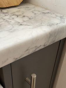 A close up of a narrow kitchen cabinet under a white, marbled worktop. I am sure that this is actually green, but have been assured by everyone else that it is, in fact, grey.